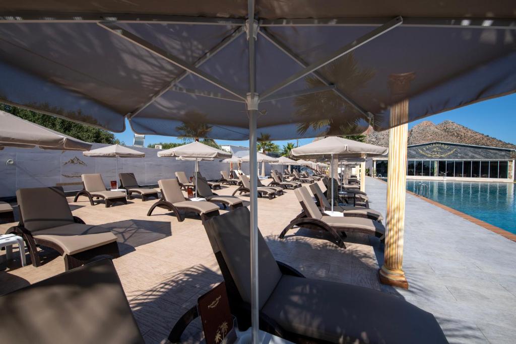 a group of lounge chairs and umbrellas next to a swimming pool at Paradice Hotel Luxury Suites-Near zorbas Beach-FREE Breakfast in Stavros