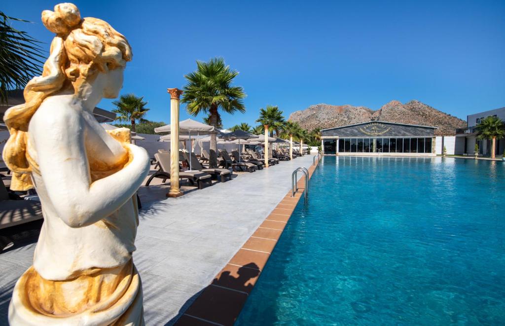 a statue next to a swimming pool at a resort at Paradice Hotel Luxury Suites-Near zorbas Beach-FREE Breakfast in Stavros