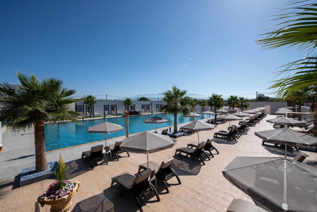 a pool with chairs and umbrellas in a resort at Paradice Hotel Luxury Suites-Near zorbas Beach-FREE Breakfast in Stavros