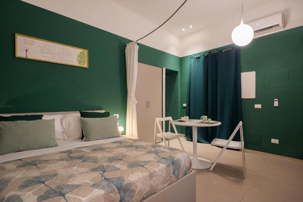 um quarto com paredes verdes, uma cama e uma mesa em Aquacharme em Palermo