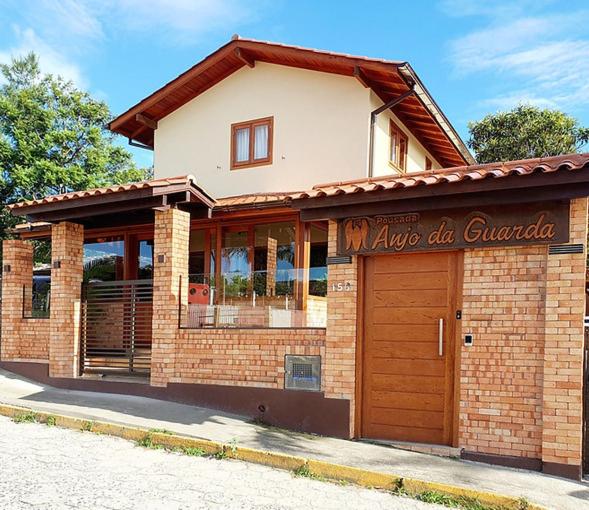 un bâtiment en briques avec un panneau devant lui dans l'établissement Pousada Anjo da Guarda, à Guarda do Embaú