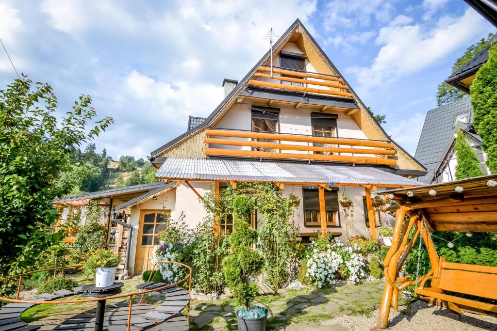 a house with a thatched roof and a garden at Ciukrowa Chatka z jacuzzi in Poronin