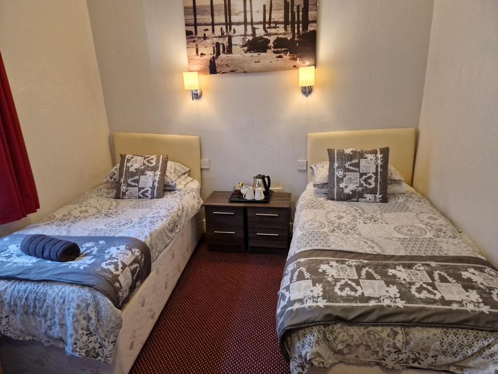 - une chambre avec 2 lits et une table de nuit dans l'établissement Stafford House, à Blackpool