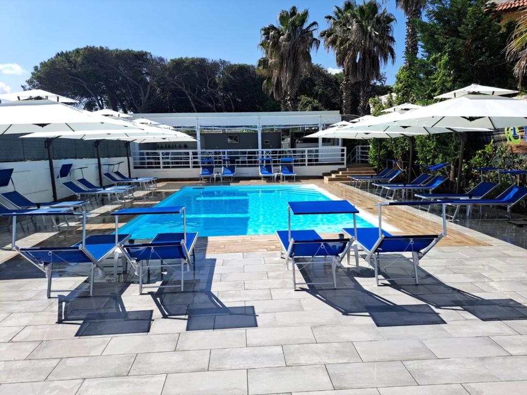 a swimming pool with blue chairs and umbrellas at Le Pinède in Licola