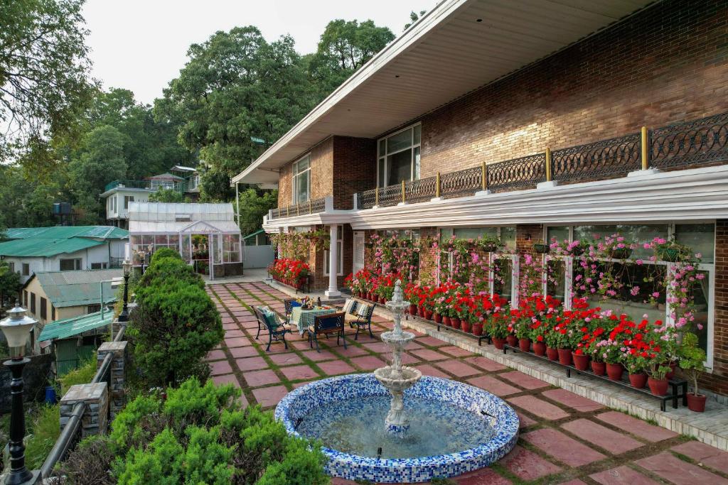 Un patio al aire libre con una fuente y flores en un edificio. en Lohonostays Soni Estate, en Mussoorie
