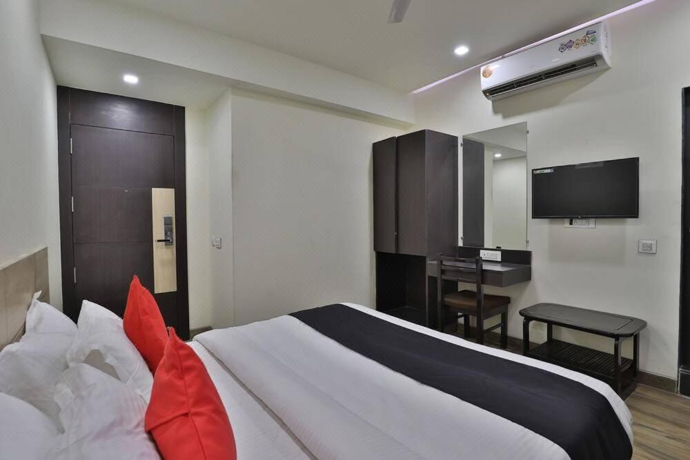 a bedroom with a bed and a desk and a television at Hotel Grand Ambience in Gandhidham