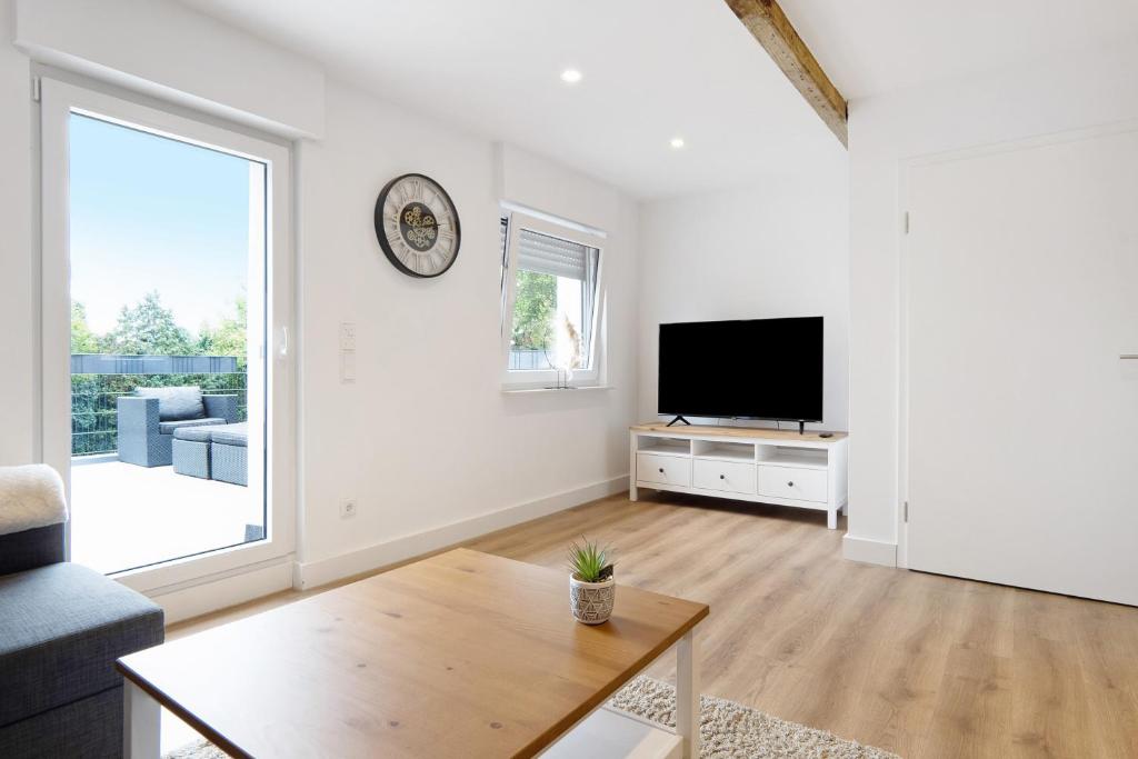 a white living room with a tv and a table at Appartment Weiden in Gronau