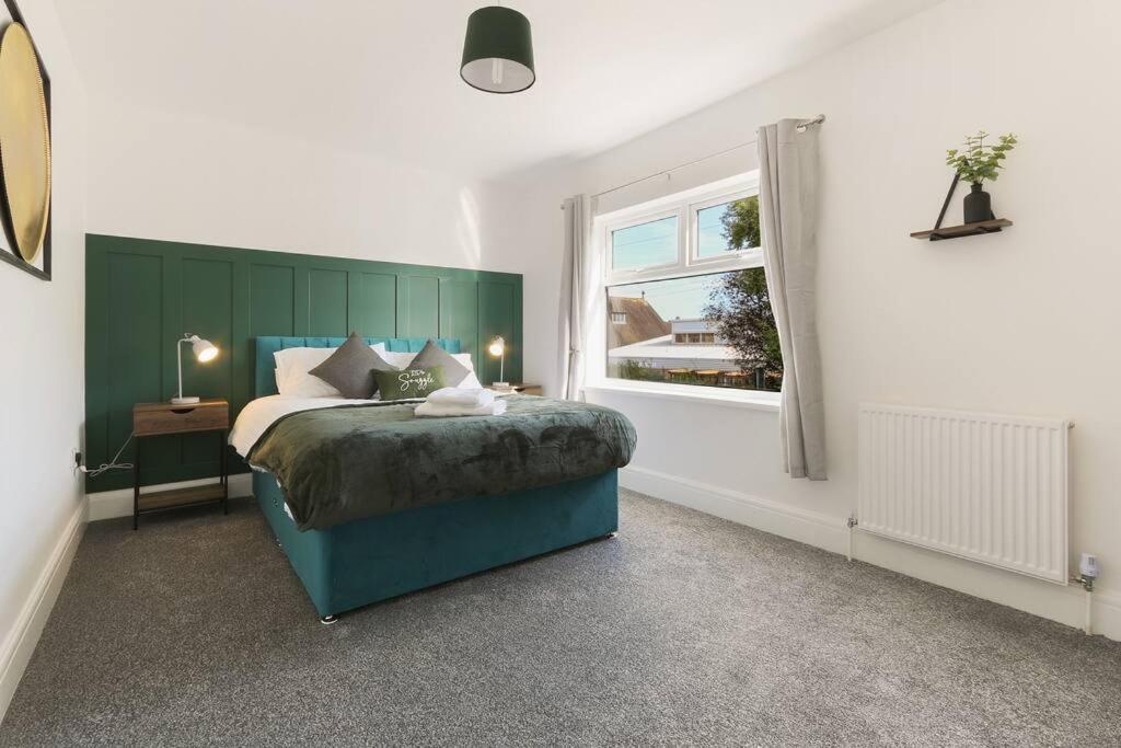 a bedroom with a bed with a green headboard and a window at Modern home near Alexandra Dock in Great Coates