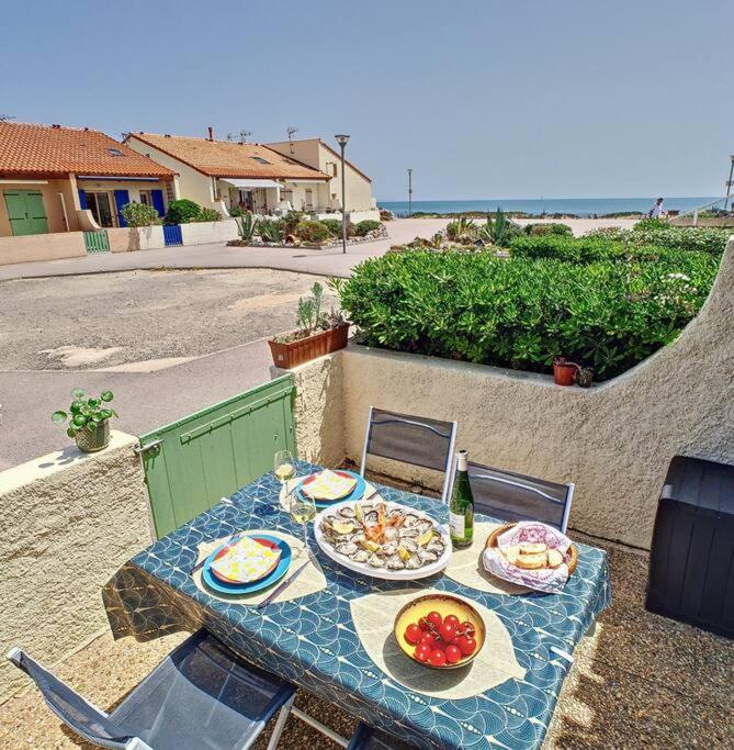- une table avec des assiettes de nourriture au-dessus d'une terrasse dans l'établissement Petite maison à la plage dans résidence naturiste, à Leucate