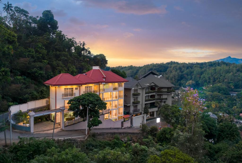 a building on a hill with a sunset in the background at Hotel Cassendra in Kandy