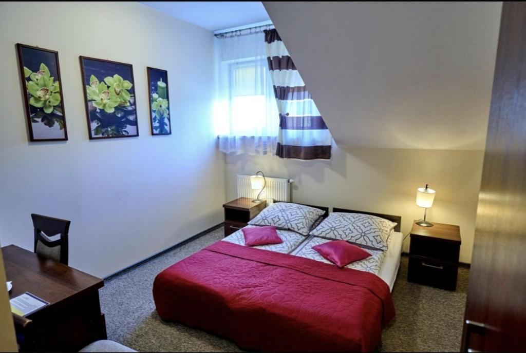 sypialnia z łóżkiem z czerwoną pościelą i biurkiem w obiekcie Zajazd Laguna w mieście Trojanów
