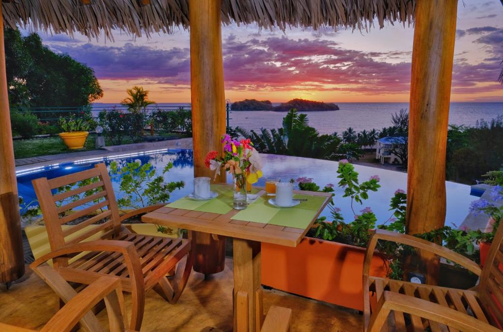 una mesa y sillas en un porche con vistas al océano en VILLA PANORAMA NOSY BE en Nosy Be