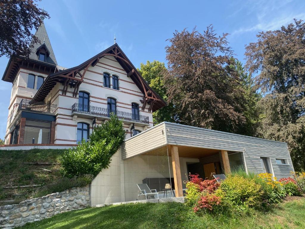 une grande maison blanche avec des chaises dans la cour dans l'établissement Le Manoir de l'Oselière & Spa, à Les Hauts-Geneveys