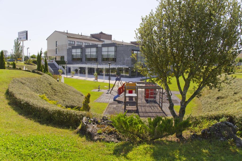 a playground in a park with a tree and a building at Hq La Galeria in Burgos