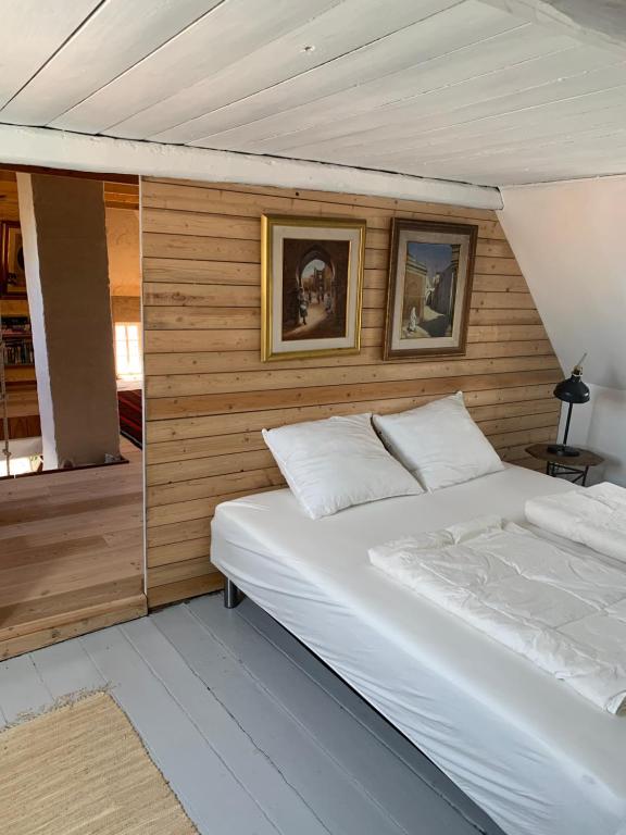 a bedroom with a white bed and two pictures on the wall at Timberframe house near Marstal Harbour in Marstal
