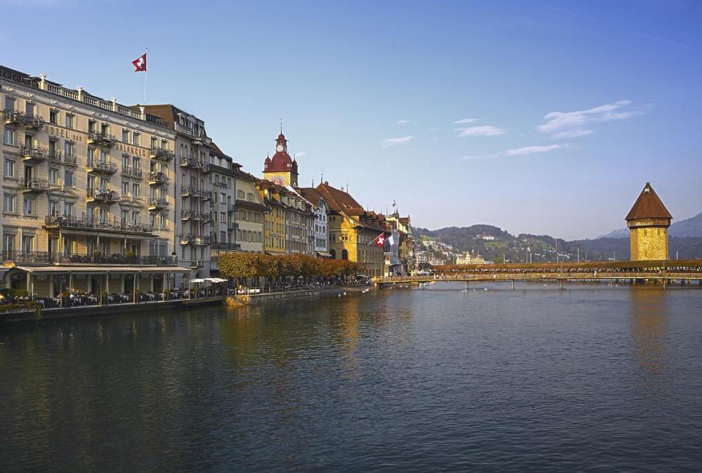 a river in a city with buildings and a bridge at Hotel des Balances in Lucerne