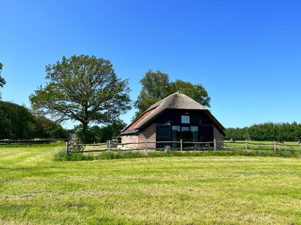 ein kleines Gebäude auf einem Feld mit einem Zaun in der Unterkunft Schaapskooi Sandenburg in Doorn