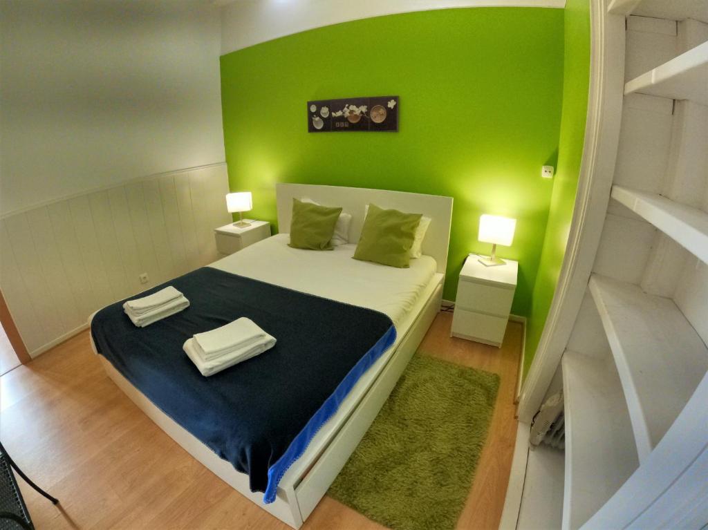 um quarto com uma cama com uma parede verde em Lisbon T2 apartment in typical villa in Sapadores Lisbon em Lisboa