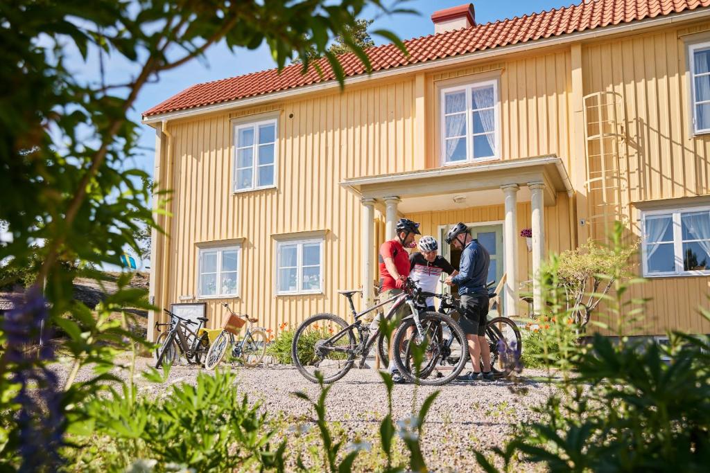 three people standing in front of a yellow house at Vandrarhemmet Gammelgården in Bengtsfors