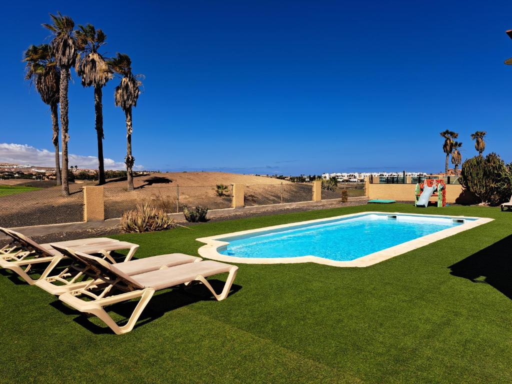 a swimming pool with two lounge chairs next to it at Villa Yeromi in La Guirra