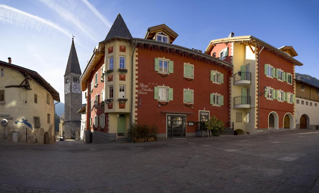 a large building with a clock tower in a street at Albergo Cavallino Bianco in Rumo