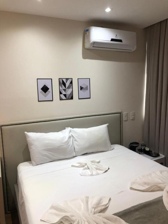 Un dormitorio con una cama blanca y aire acondicionado. en Apart-hotel TrueAmérica, en Campos dos Goytacazes