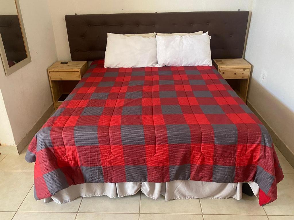 uma cama com um cobertor xadrez vermelho e preto em Aeropark Residencial(1) em Maputo