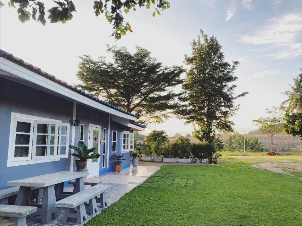 una casa azul con una mesa de picnic en el patio en บ้านสวนจันทร์เจ้า, en Wang Nam Khiao