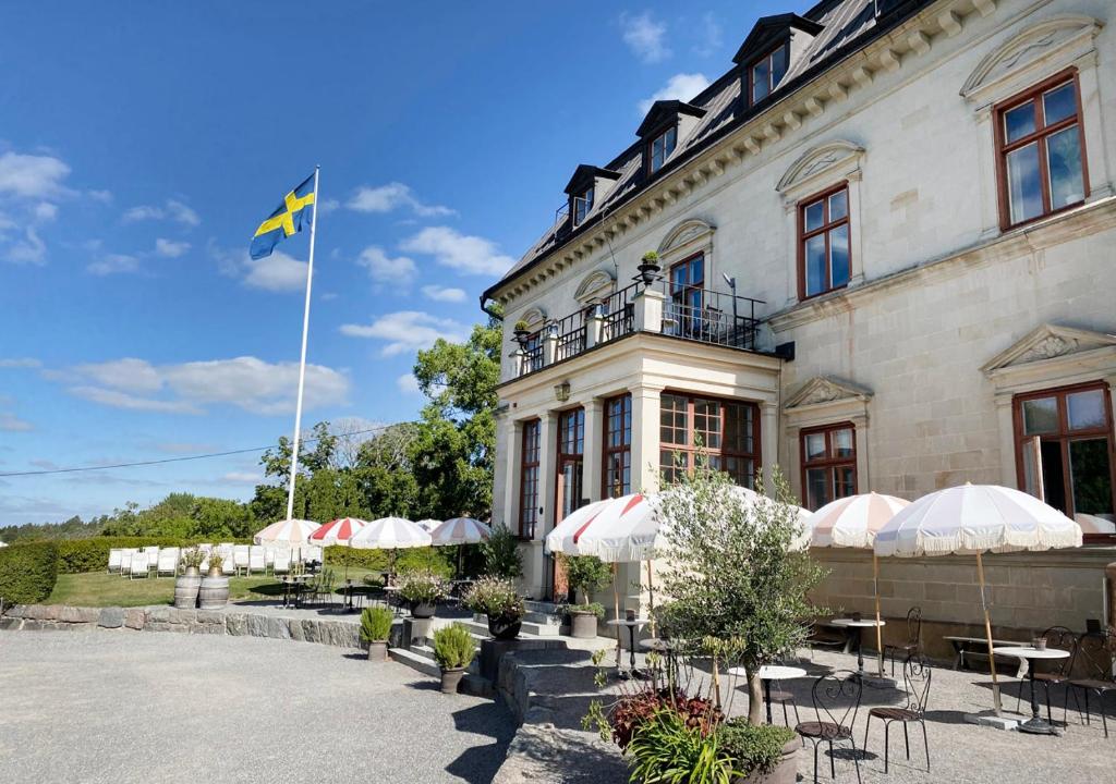 una bandera ondeando frente a un edificio con mesas y sombrillas en Görvälns Slott, en Järfälla