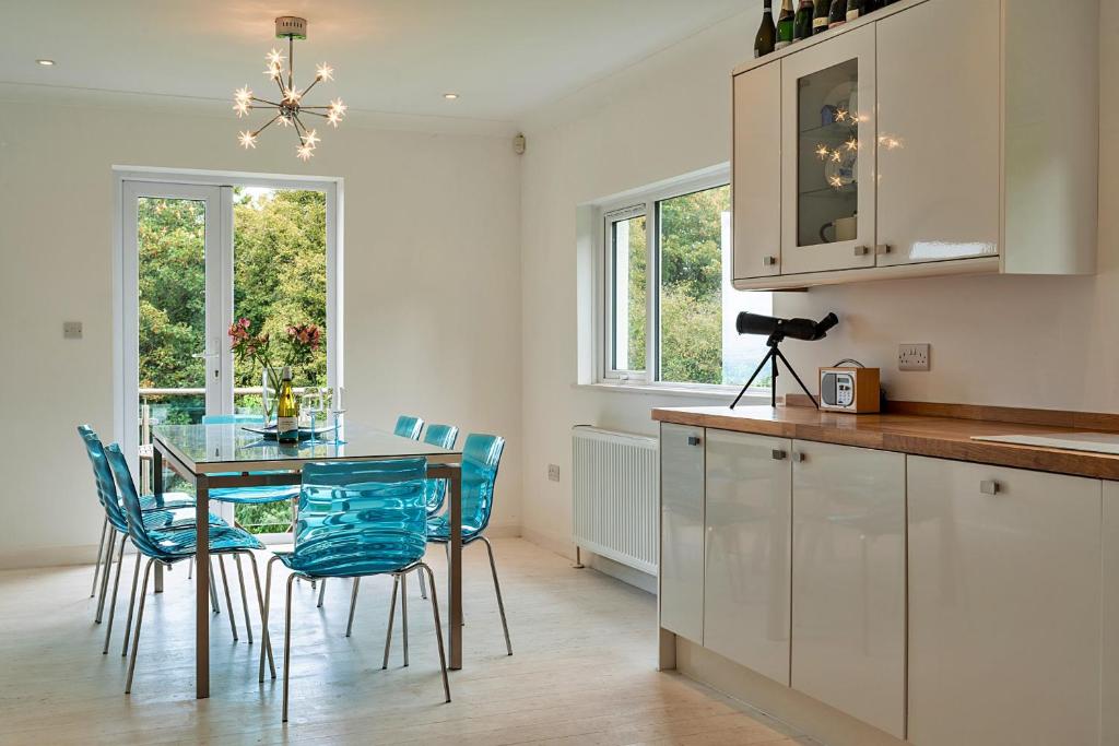 cocina con mesa de cristal y sillas azules en Finest Retreats - The View en Shaldon