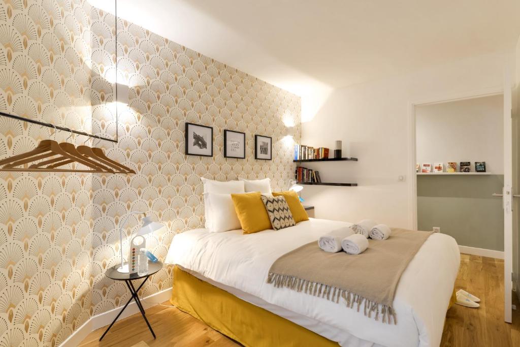 a bedroom with a large white bed with yellow pillows at Sweet Inn - Chevalier Saint Georges in Paris