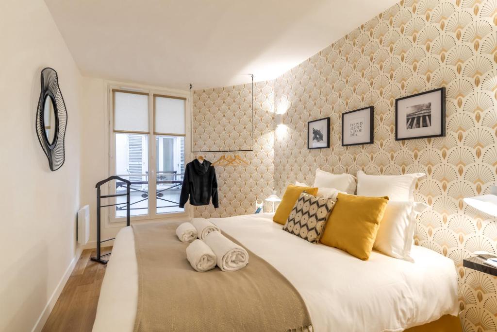 a bedroom with a large white bed with yellow pillows at Sweet Inn - Chevalier Saint Georges in Paris