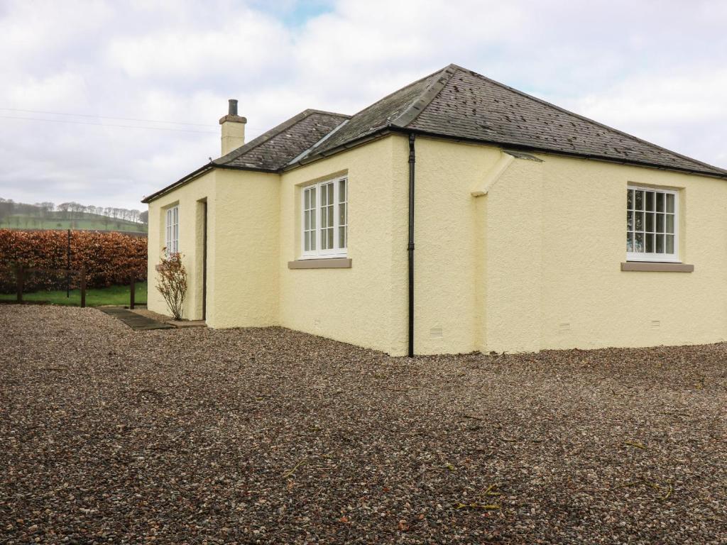 a yellow house on a gravel driveway at Bankhead of Lour Bungalow in Forfar