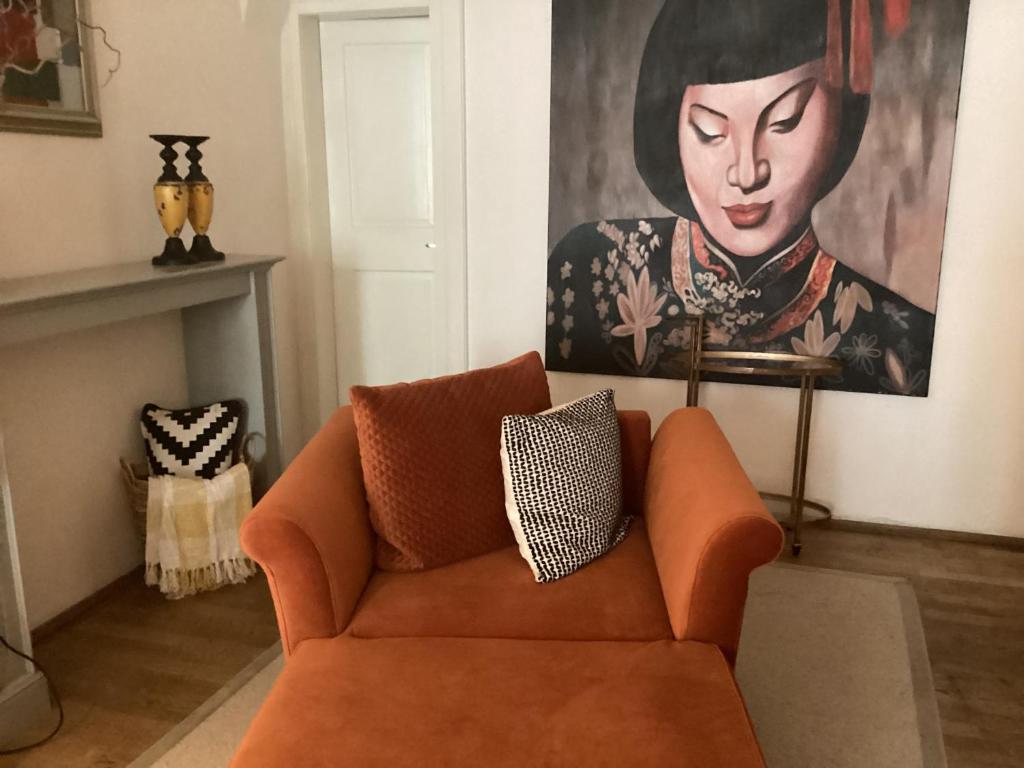 an orange couch in a living room with a painting at Nana Macs in Prague