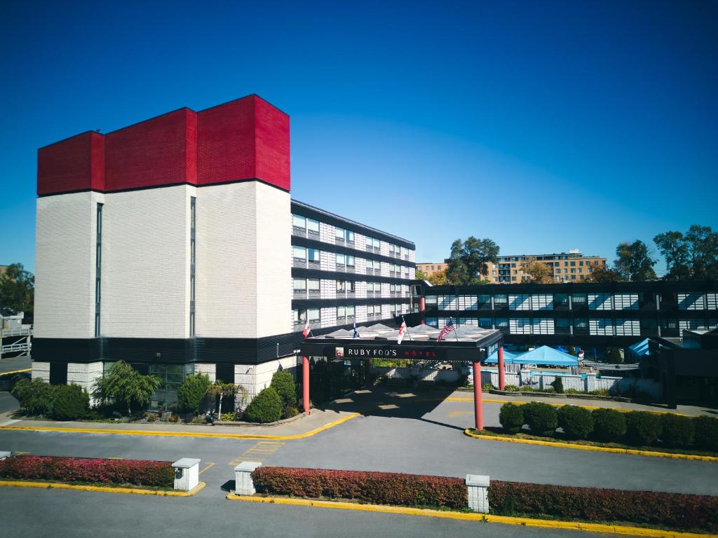un gran edificio blanco y rojo con aparcamiento en Hotel Ruby Foo's, en Montreal