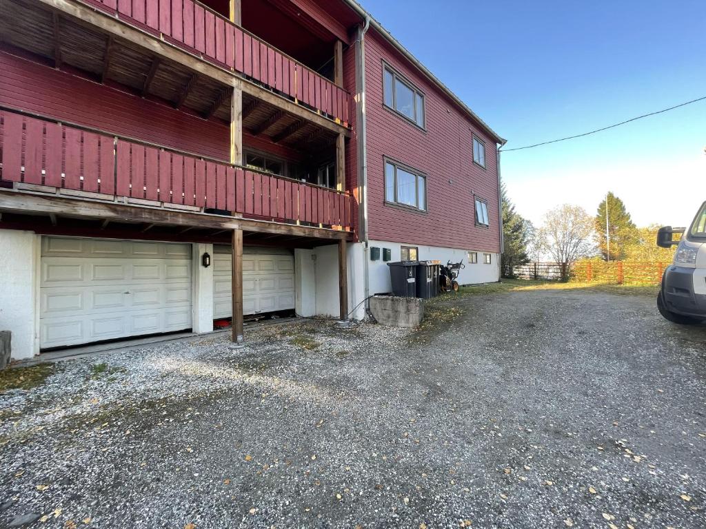 een rood gebouw met twee garagedeuren en een parkeerplaats bij Nice apartment near to city center of Tromso in Tromsø