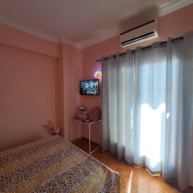 a bedroom with a bed and a tv and a window at Riga Fereou apartments in Patra