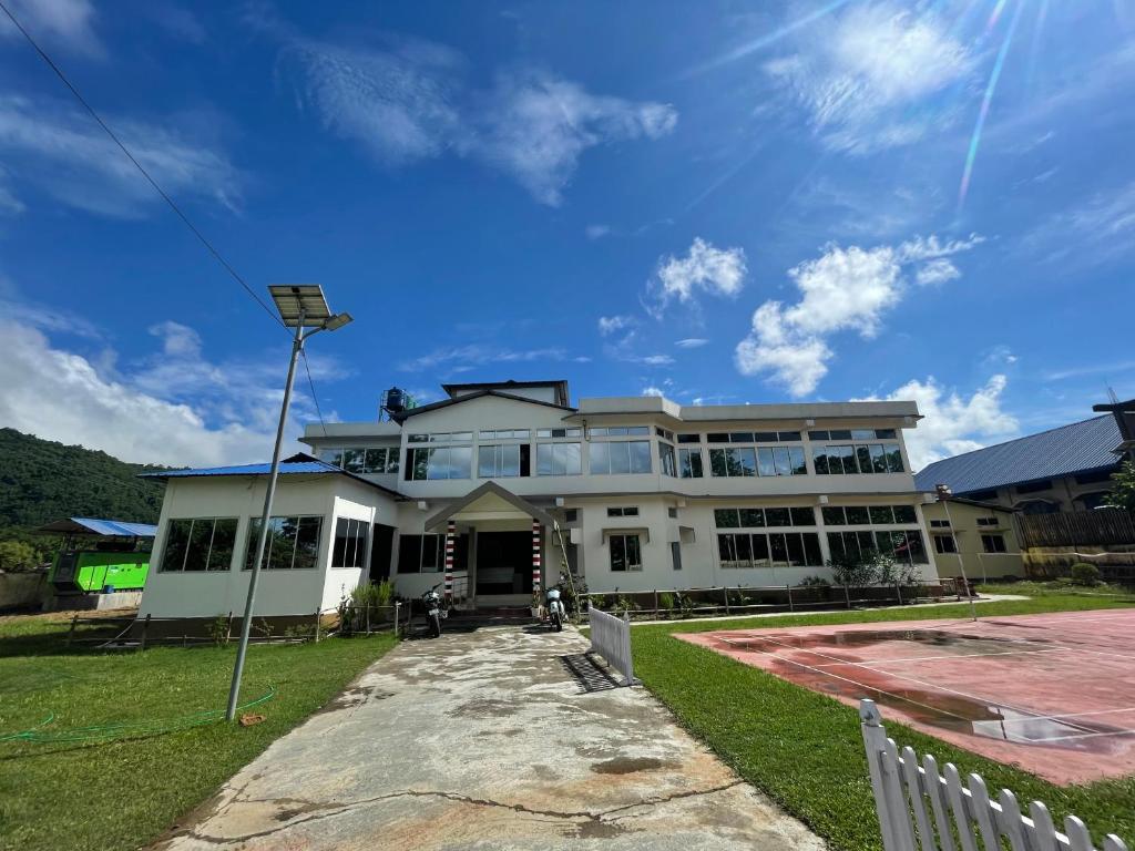 una grande casa bianca con una recinzione di fronte di Le Green Kaziranga a Hatikhuli