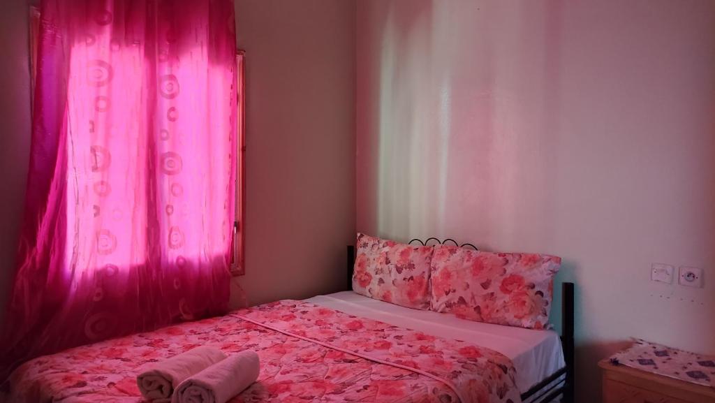 - une chambre avec des rideaux roses et un lit avec deux oreillers dans l'établissement Myhouse Todgha, à Tinghir