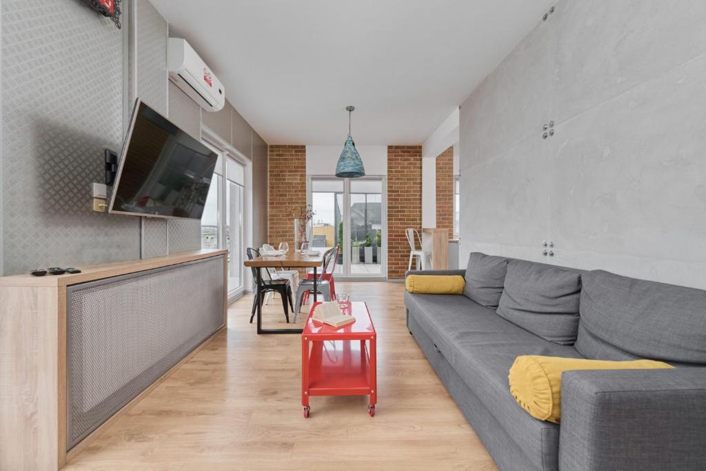 een woonkamer met een grijze bank en een tafel bij Beautiful Apartment with Spacious Balcony by Renters in Wrocław