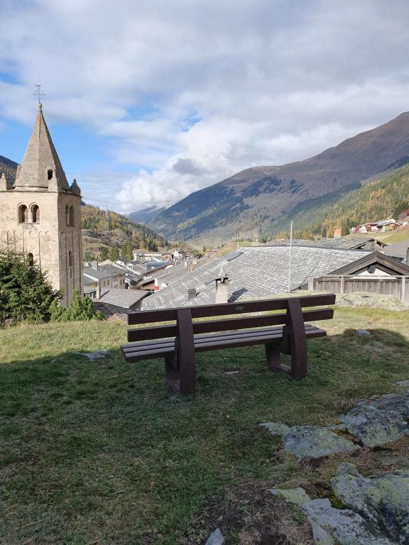 a bench sitting in the grass near a church at L'ancien hospice in Bourg-Saint-Pierre