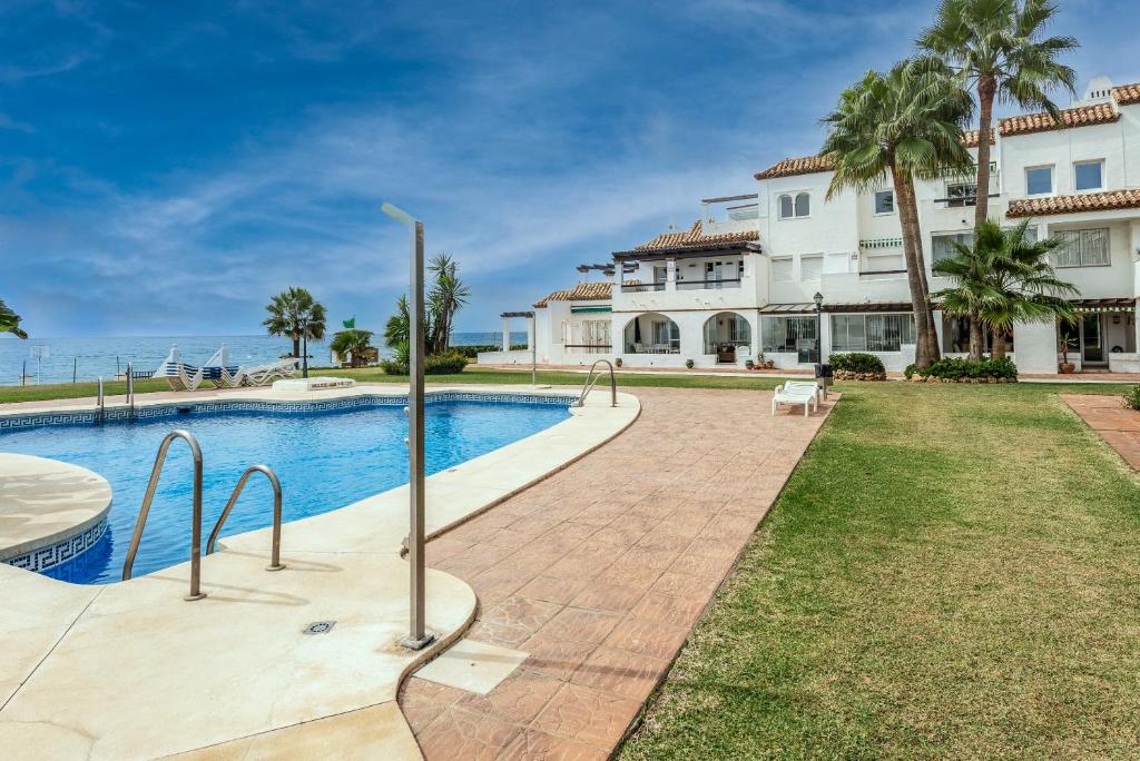 a villa with a swimming pool in front of a house at Playa Lucera in Sitio de Calahonda