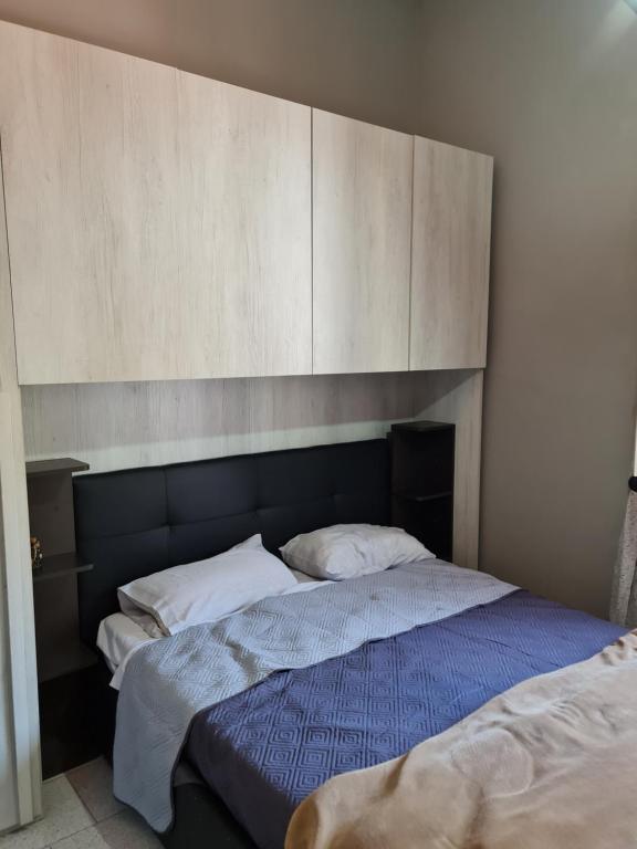 een slaapkamer met een bed met een houten hoofdeinde bij Home Ciampino in Ciampino