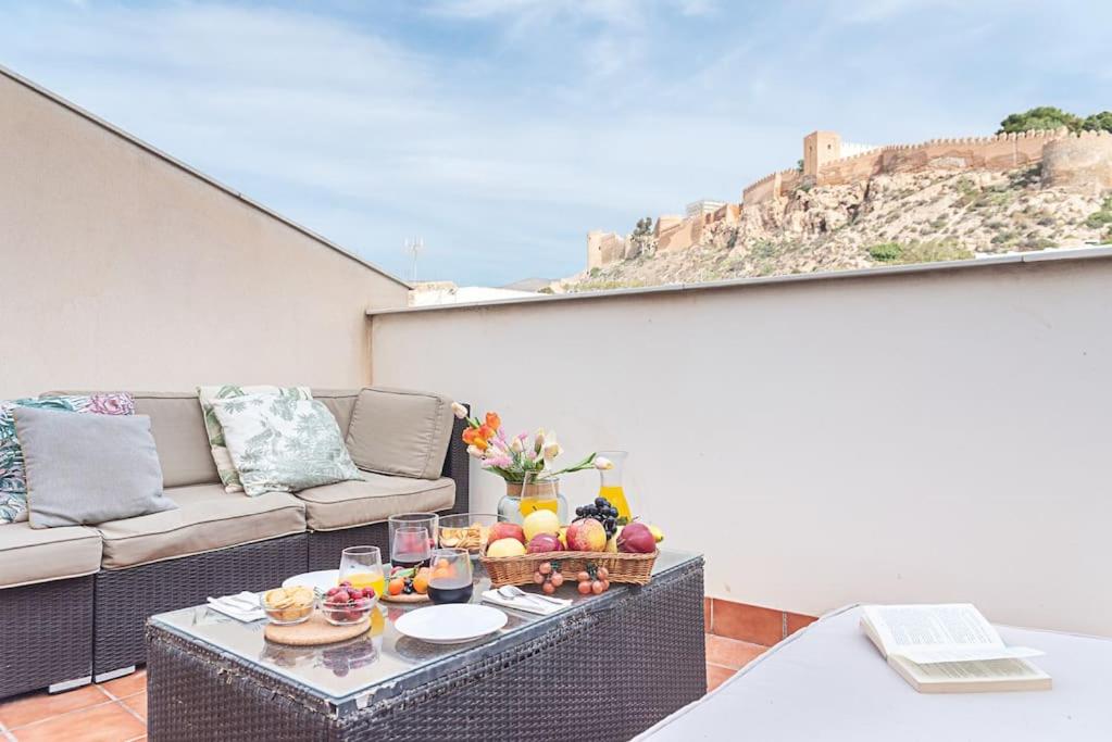 Un balcón con una mesa con fruta y un sofá. en Casa flamenca a los pies de la Alcazaba, en Almería