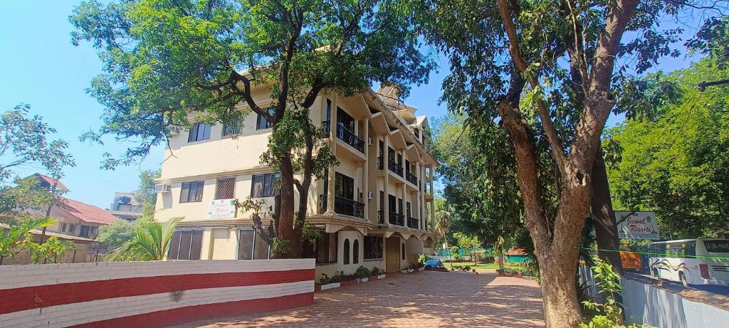 un grand bâtiment avec un arbre devant dans l'établissement Jewel Resort, à Lonavala