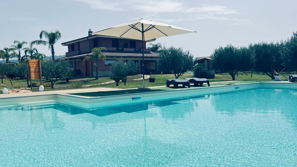 una piscina con ombrellone di fronte a una casa di B&B Casale Pietrantica Tropea a Ciaramiti