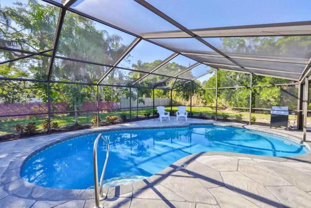 an indoor swimming pool with a large glass house with a patio at Lazy Manatee Pool Home in Bradenton