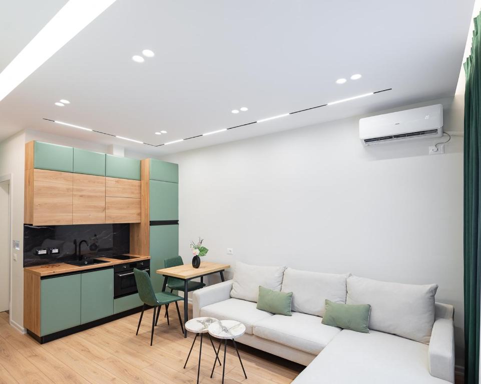 a living room with a white couch and a kitchen at Arkle Apartments 3 in Tirana