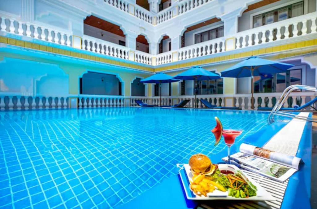 會安的住宿－Le Pavillon Hoi An Gallery Hotel & Spa，酒店游泳池设有餐桌,上面有食物