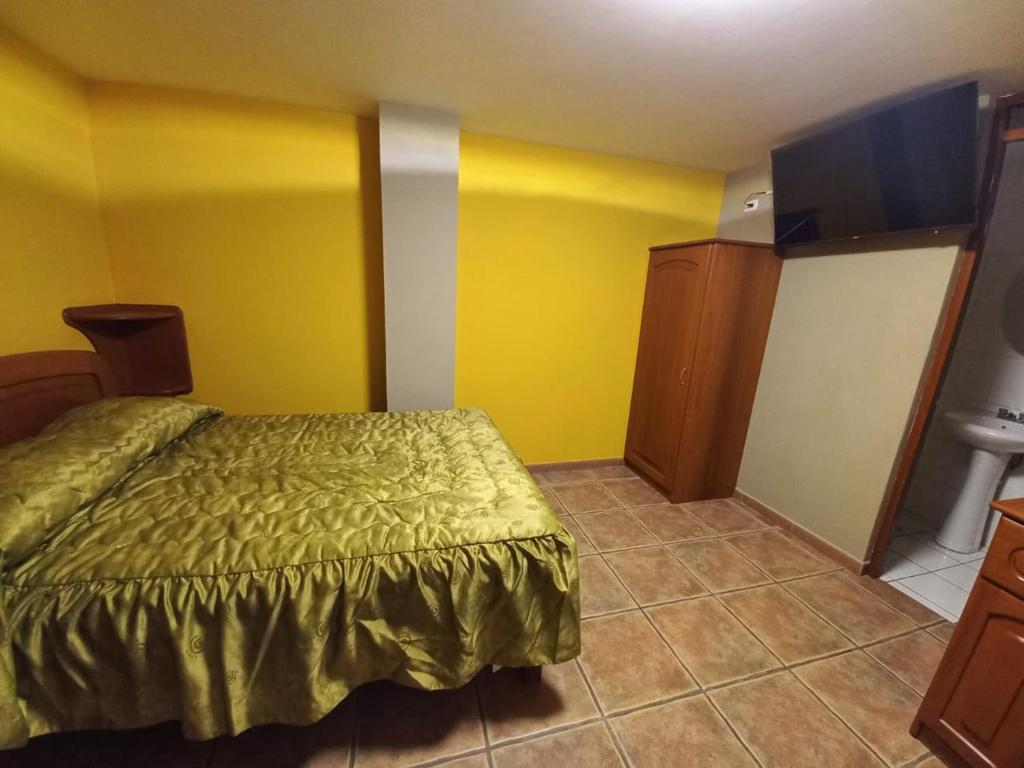 a bedroom with a bed and a yellow wall at Hotel La Villa in Arequipa